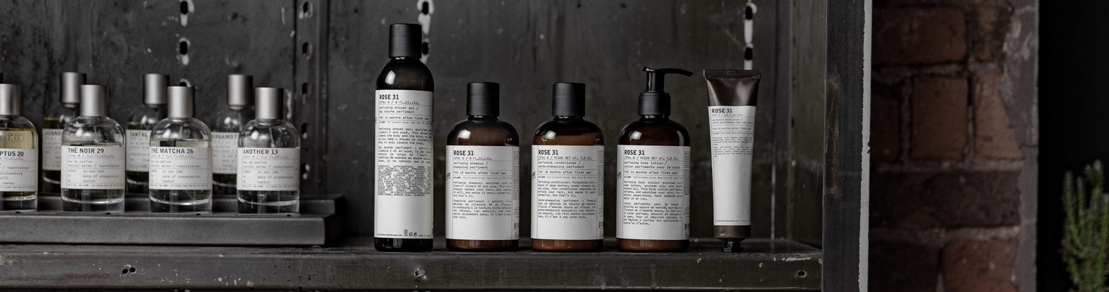 Le Labo perfuming body lotion and candles on a wooden dresser