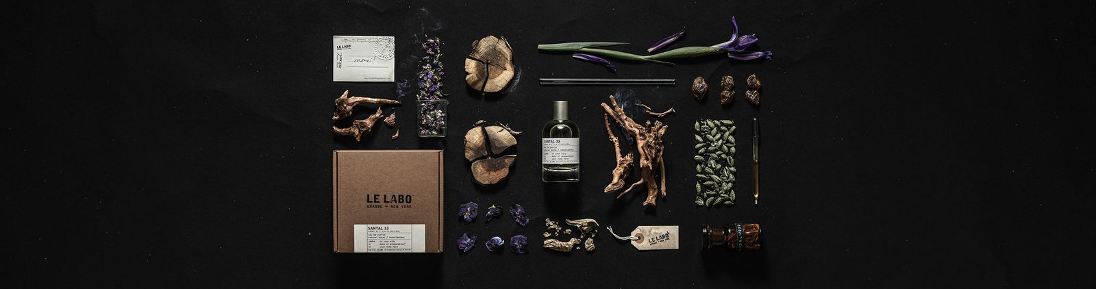 Le Labo Santal 33 eau de parfum bottle with sandalwood, cardamom pods, iris and violet on black