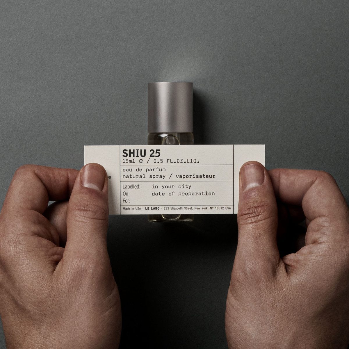Le Labo Shiu 25 eau de parfum bottle held in two hands, hand-written label